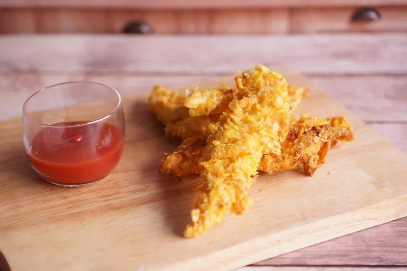 Aiguillettes de poulet panées aux corn flakes, dorées et croustillantes, avec leur sauce