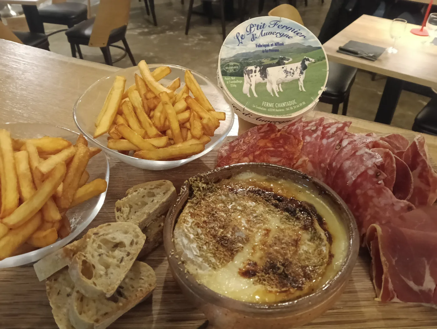 Fromage fermier d'Auvergne rôti, frites, charcuterie et pain sur une planche