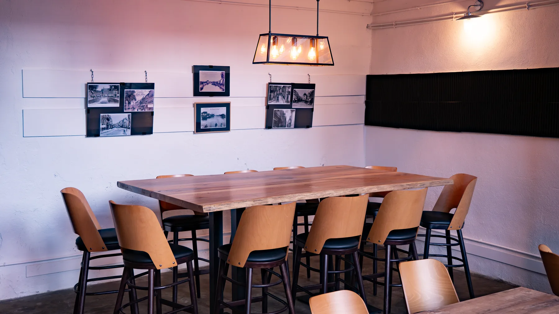 La grande table haute de la salle, chaises en bois et photos anciennes de Montluçon au mur