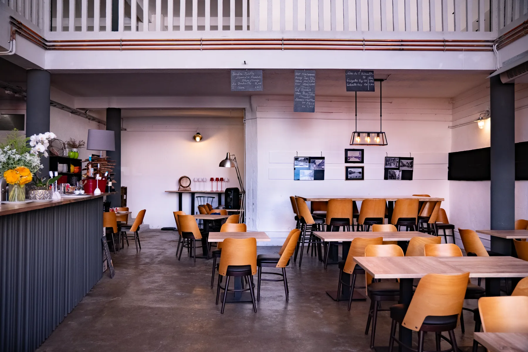 La salle de la rôtisserie : comptoir fleuri, tables en bois, ardoises des vins et photos anciennes