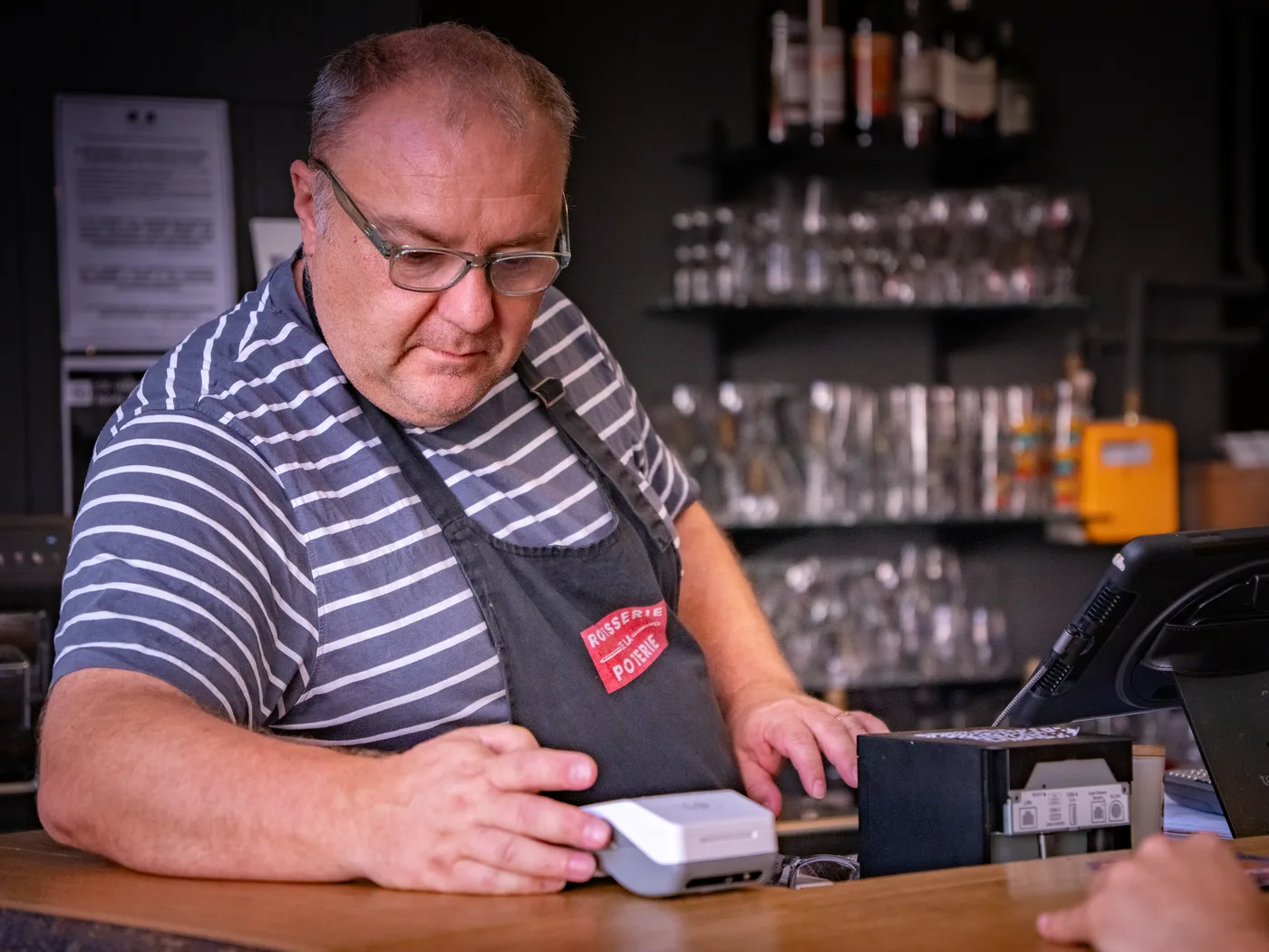 Vincent en tablier Rôtisserie de la Poterie, concentré derrière le comptoir